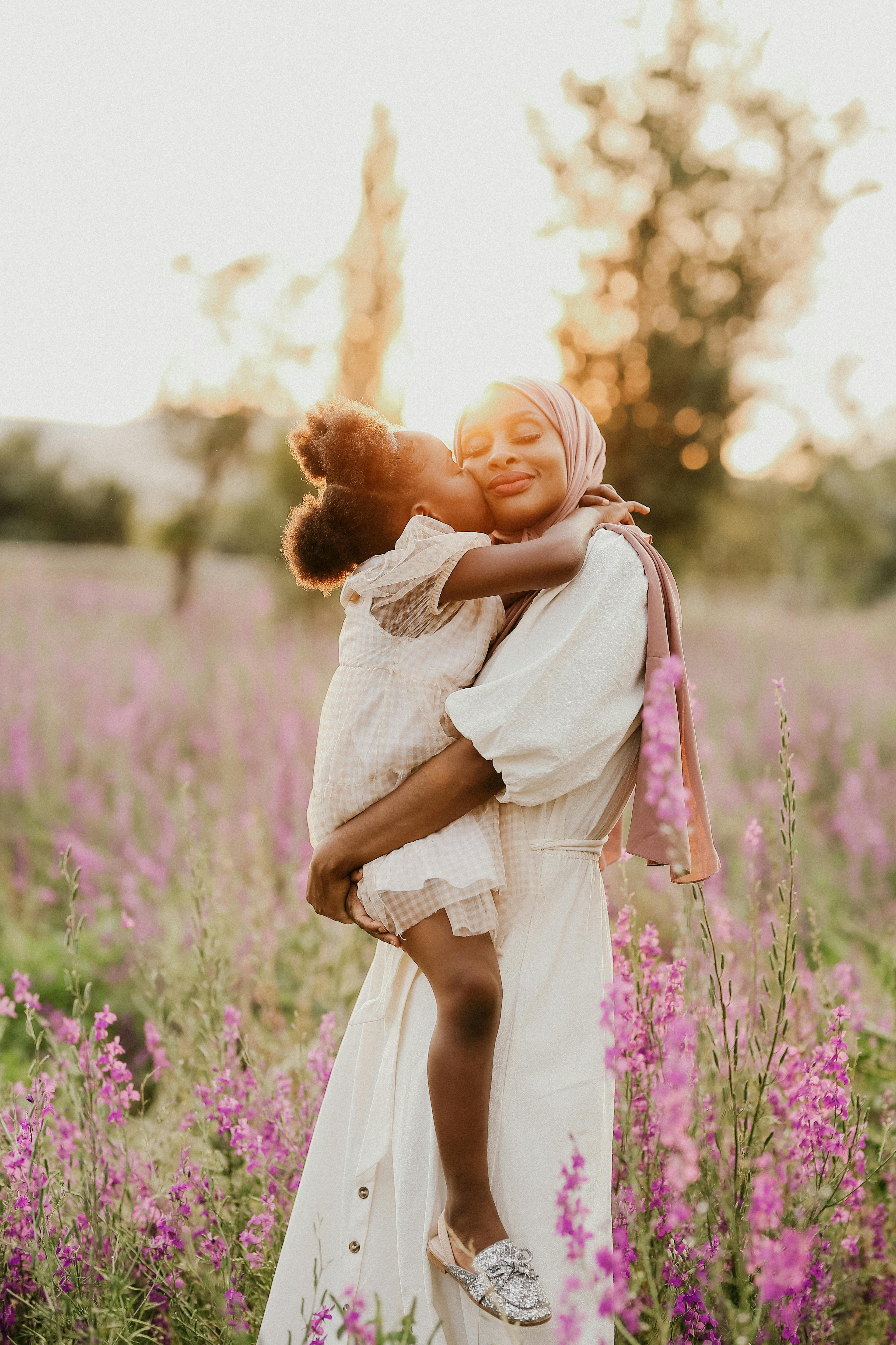 Woman embracing a child in a field of pink flowers with a blurred background