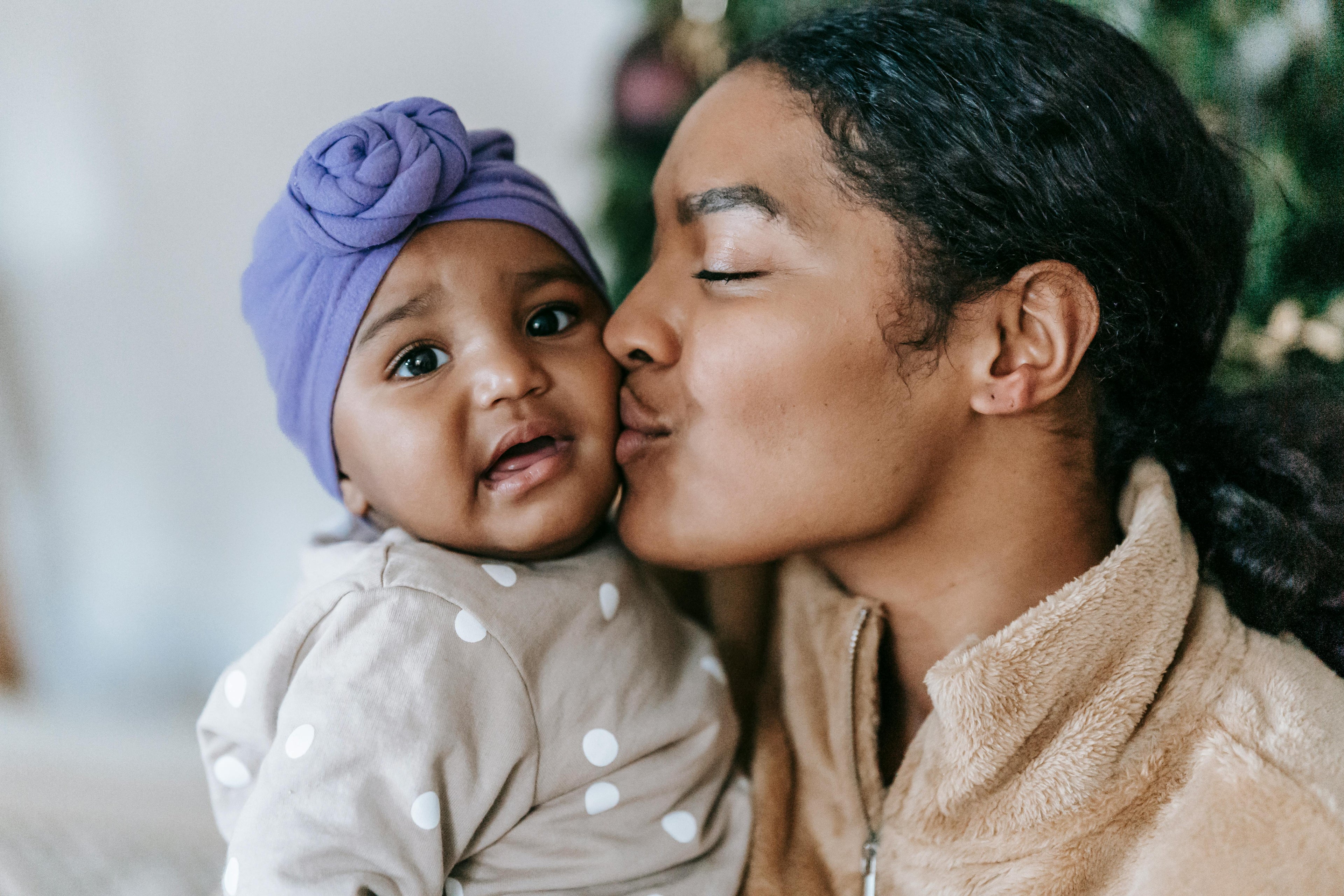 Woman kissing a baby on the cheek with a blurred background